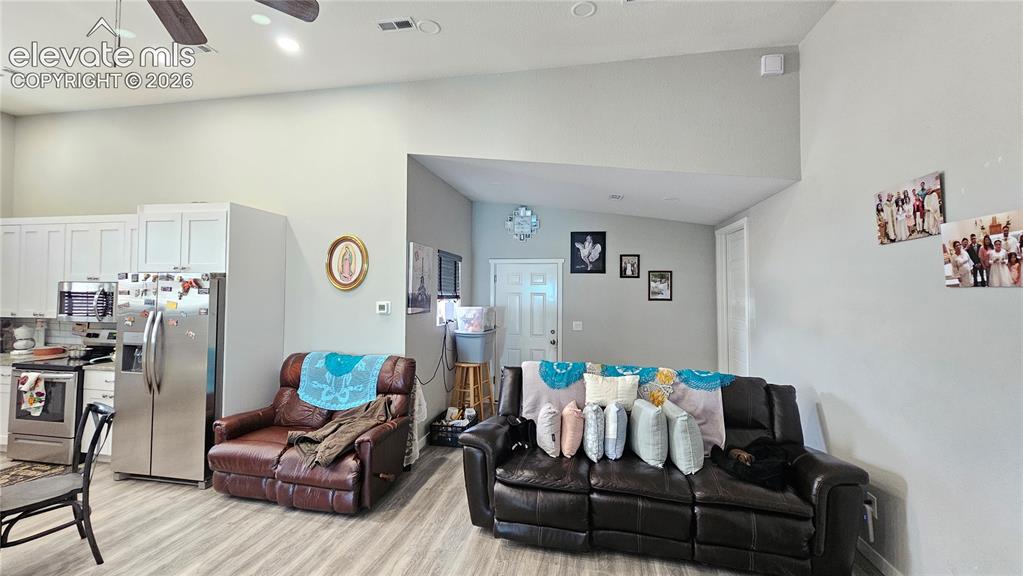 Image 17 of 48: Vaulted ceilings enhance this open-concept space featuring wood-finish floo
