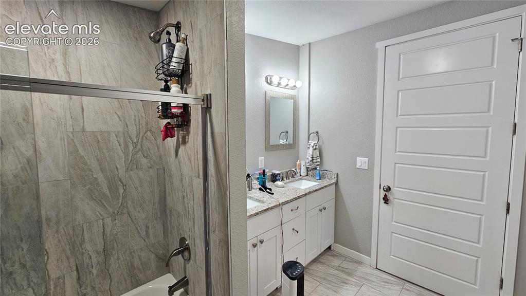Image 31 of 48: Bathroom featuring a dual vanity with granite countertops, white cabinetry,