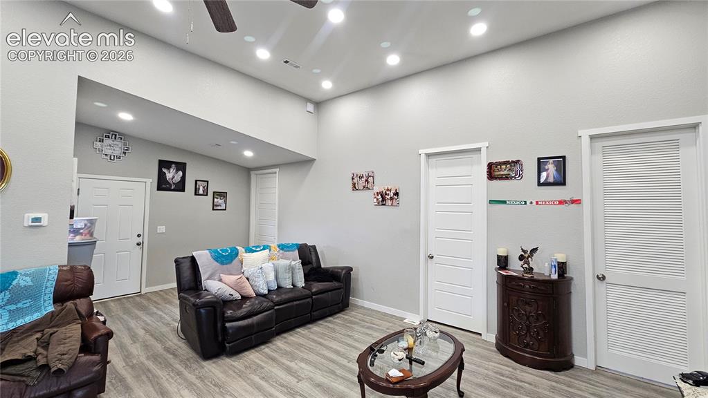 Image 33 of 48: Spacious living area featuring light gray walls, wood-finish flooring, and