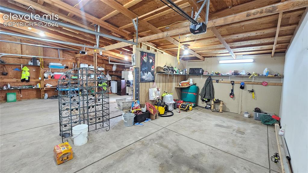 Image 37 of 48: Spacious garage featuring exposed wood beam ceilings and concrete flooring