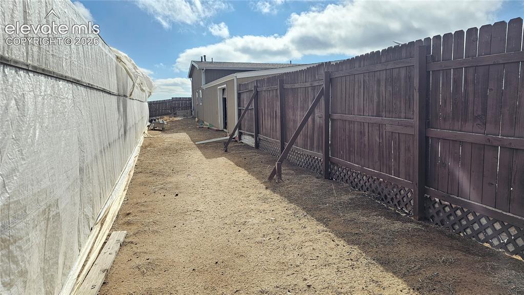 Image 4 of 48: Fenced backyard area with a wooden privacy fence, lattice detailing, and a