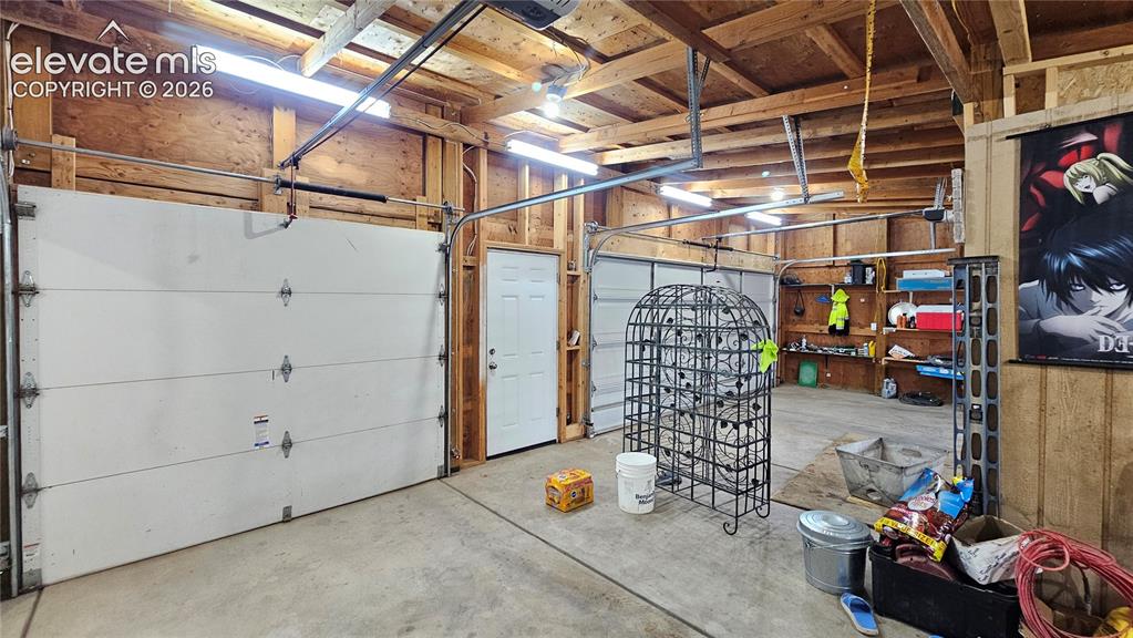 Image 40 of 48: Spacious two-car garage featuring a concrete floor and exposed wood beam ce
