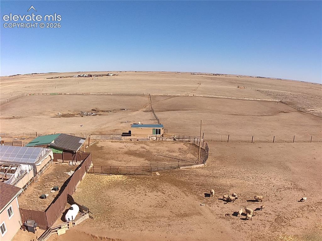 Image 45 of 48: Expansive property featuring multiple fenced enclosures, a detached outbuil