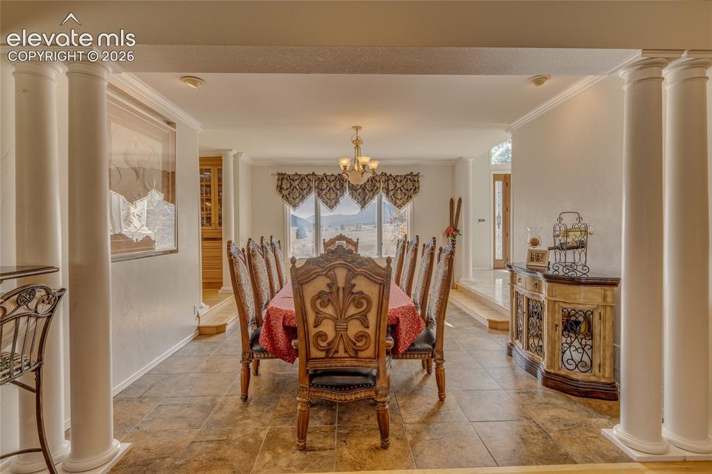 Image 10 of 32: Dining space featuring ornate columns, crown molding, and a chandelier