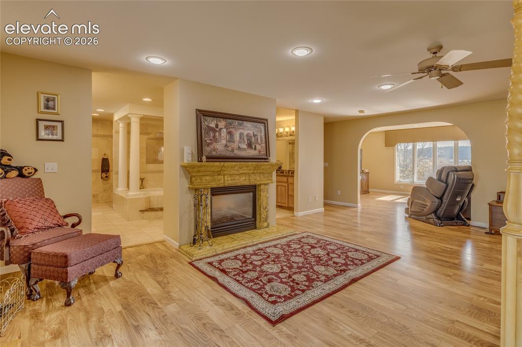 Image 15 of 32: Sitting room with a glass covered fireplace, light wood-type flooring, arch