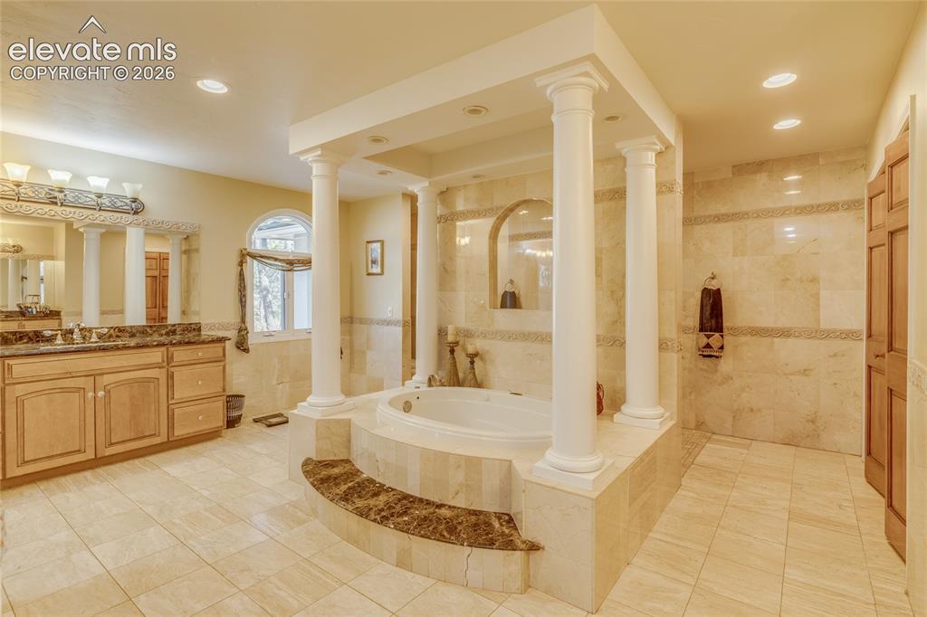 Image 16 of 32: Full bathroom featuring tile walls, a garden tub, vanity, walk in shower, a