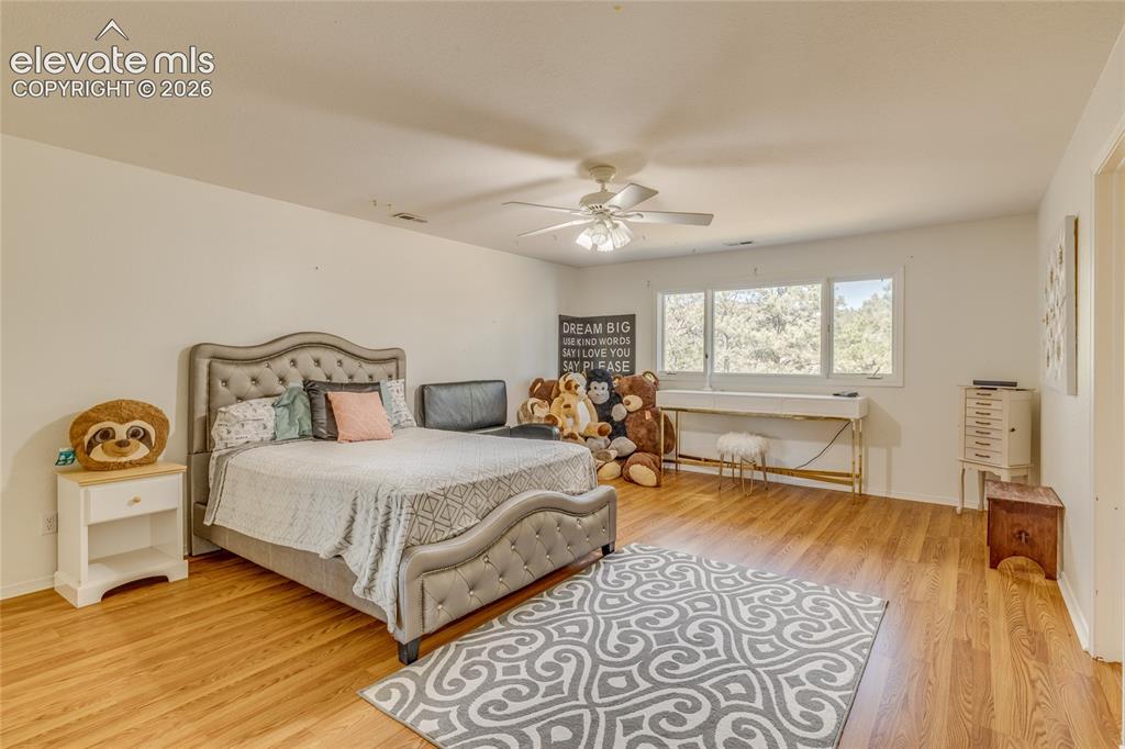 Image 23 of 32: Bedroom with light wood-type flooring, baseboard heating, and a ceiling fan