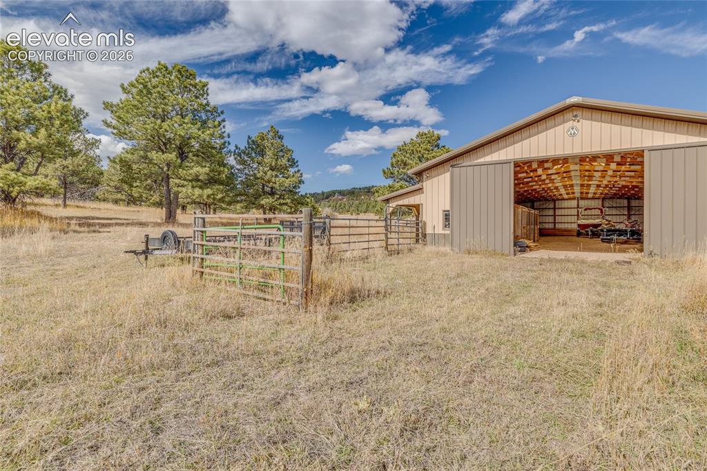 Image 27 of 32: View of yard featuring a pole building, an outbuilding, and a patio