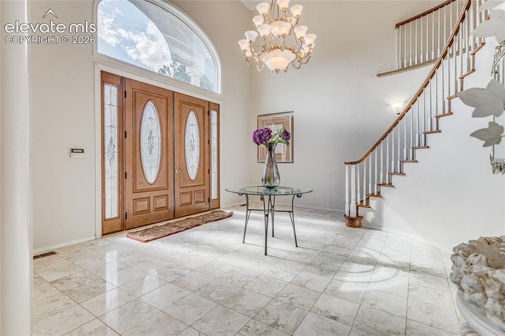 Image 4 of 32: Entrance foyer featuring a chandelier and a high ceiling