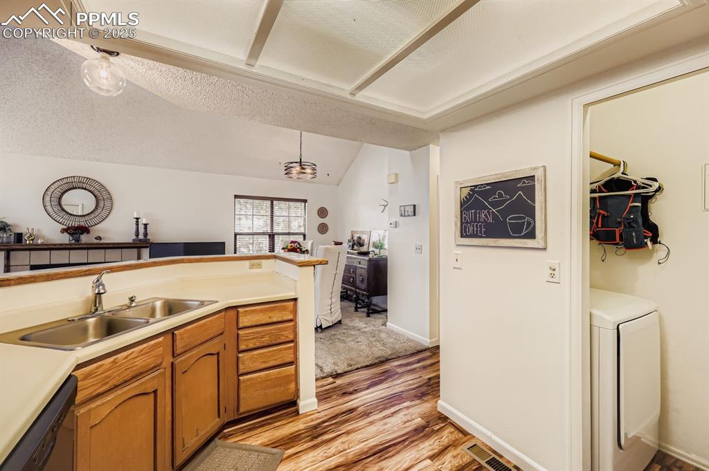 Image 10 of 25: Kitchen featuring hanging light fixtures, vaulted ceiling, light wood-style
