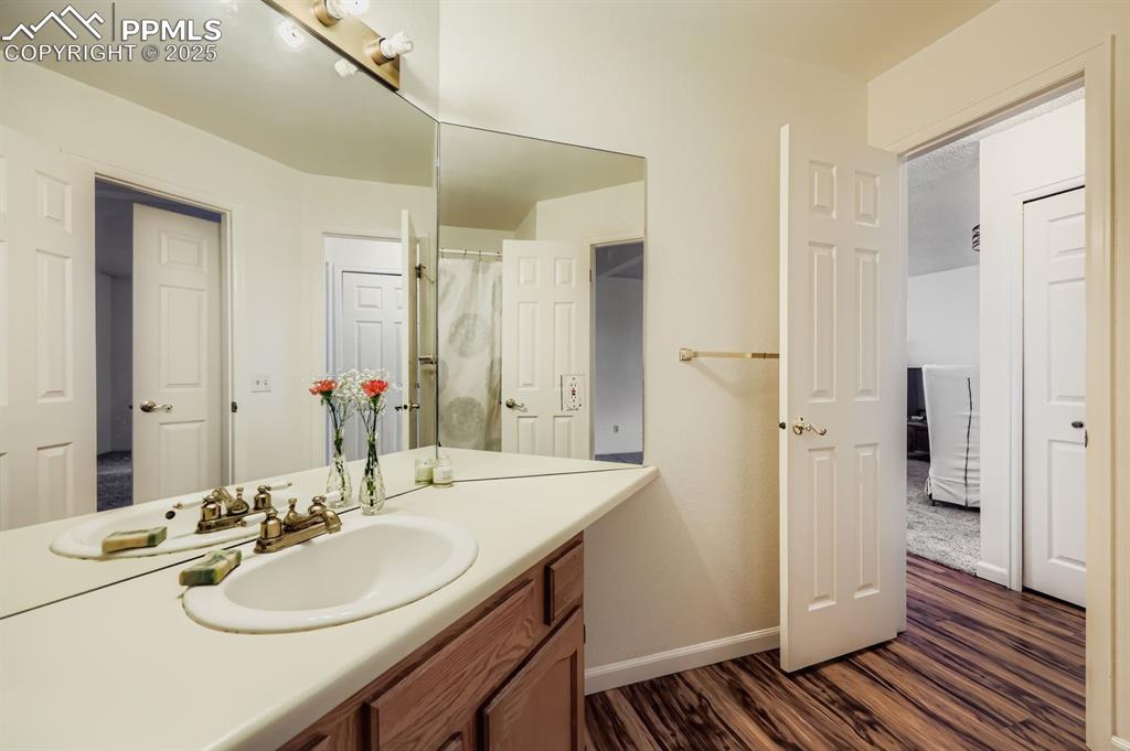 Image 15 of 25: Bathroom with vanity, dark wood finished floors, and a shower with shower c