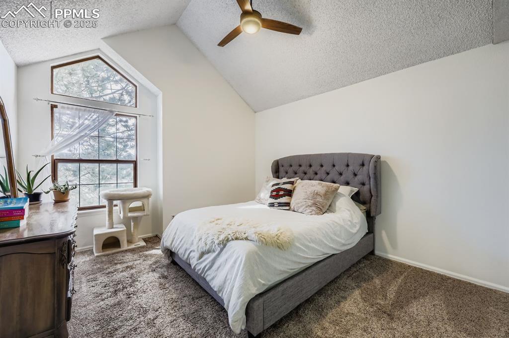Image 16 of 25: Carpeted bedroom featuring a textured ceiling, vaulted ceiling, and ceiling