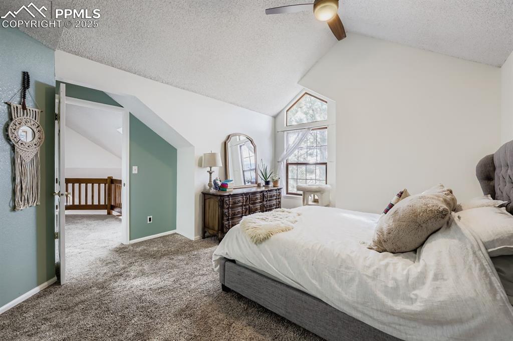 Image 17 of 25: Carpeted bedroom with a textured ceiling, high vaulted ceiling, and ceiling
