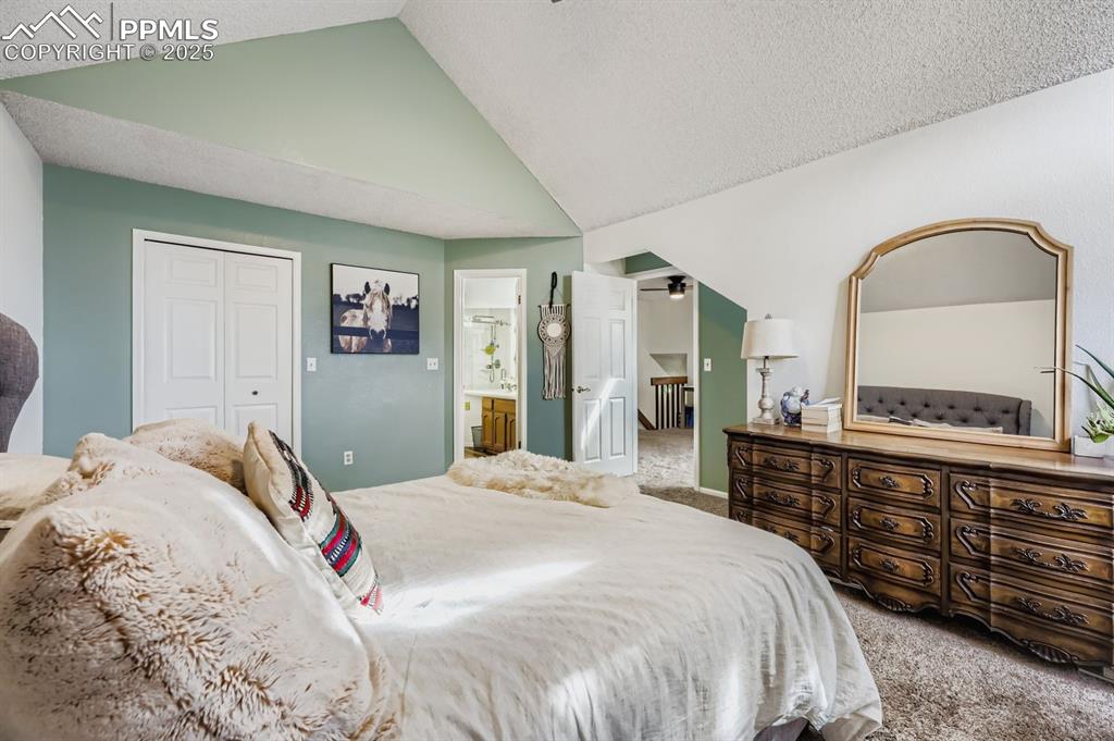 Image 18 of 25: Carpeted bedroom featuring a closet, a textured ceiling, ensuite bath, and 