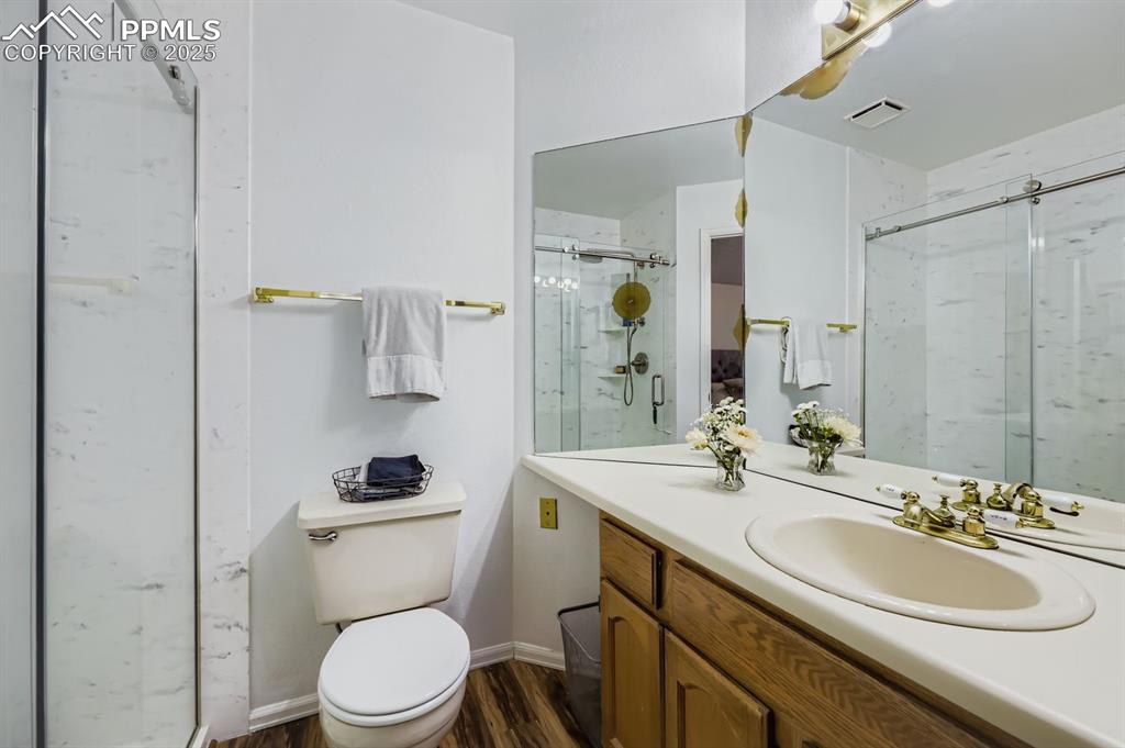 Image 19 of 25: Full bathroom with vanity, dark wood-style flooring, and a marble finish sh