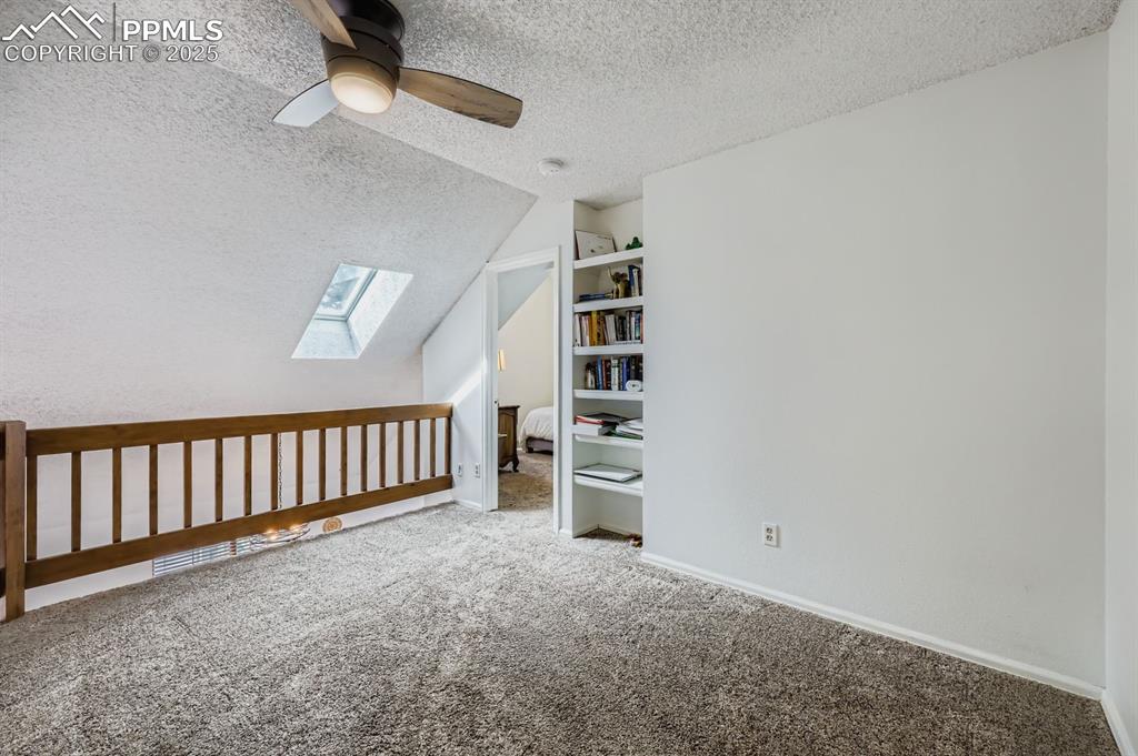 Image 21 of 25: Bonus room featuring a textured ceiling, vaulted ceiling, a skylight, carpe