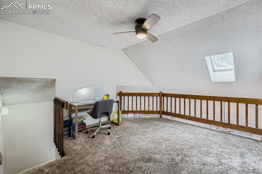 Image 22 of 25: Office area featuring lofted ceiling, a skylight, a textured ceiling, carpe