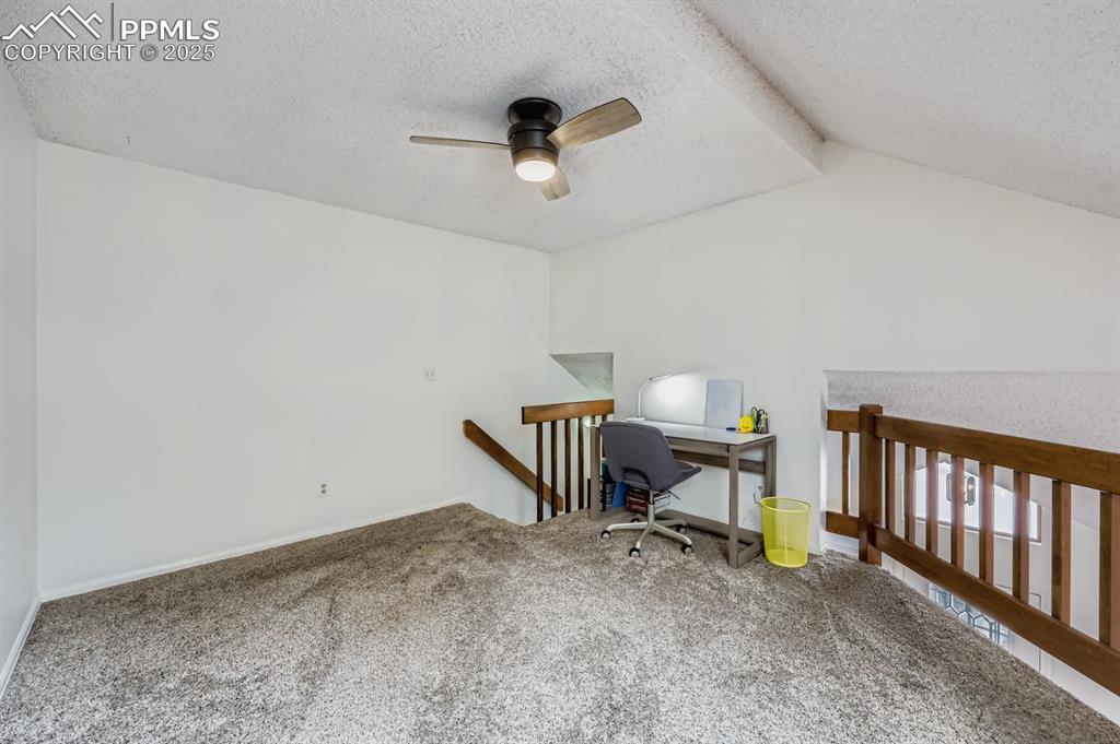 Image 23 of 25: Carpeted office space featuring a textured ceiling, vaulted ceiling, and ce