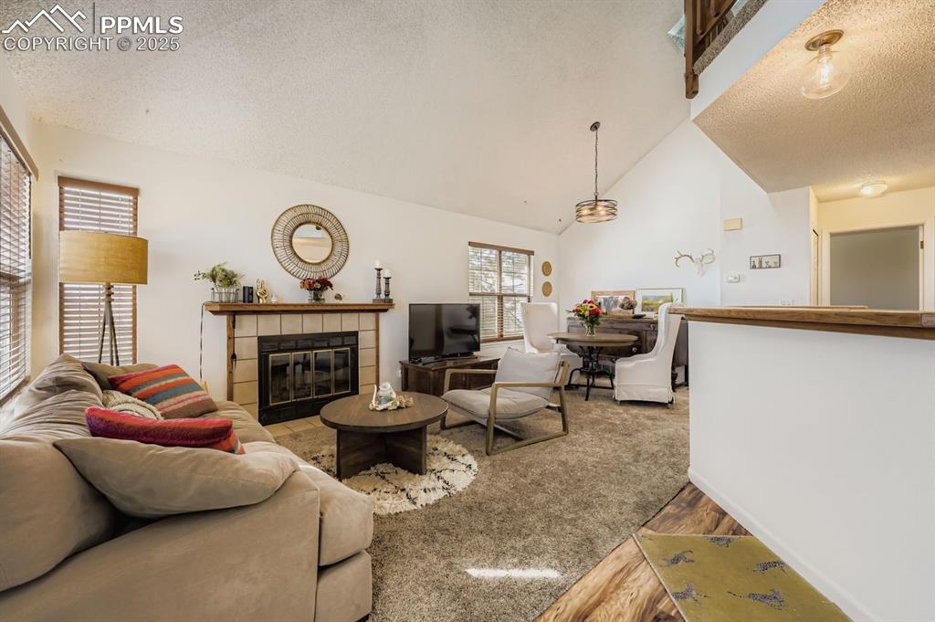 Image 3 of 25: Living room with a textured ceiling, a tile fireplace, wood finished floors