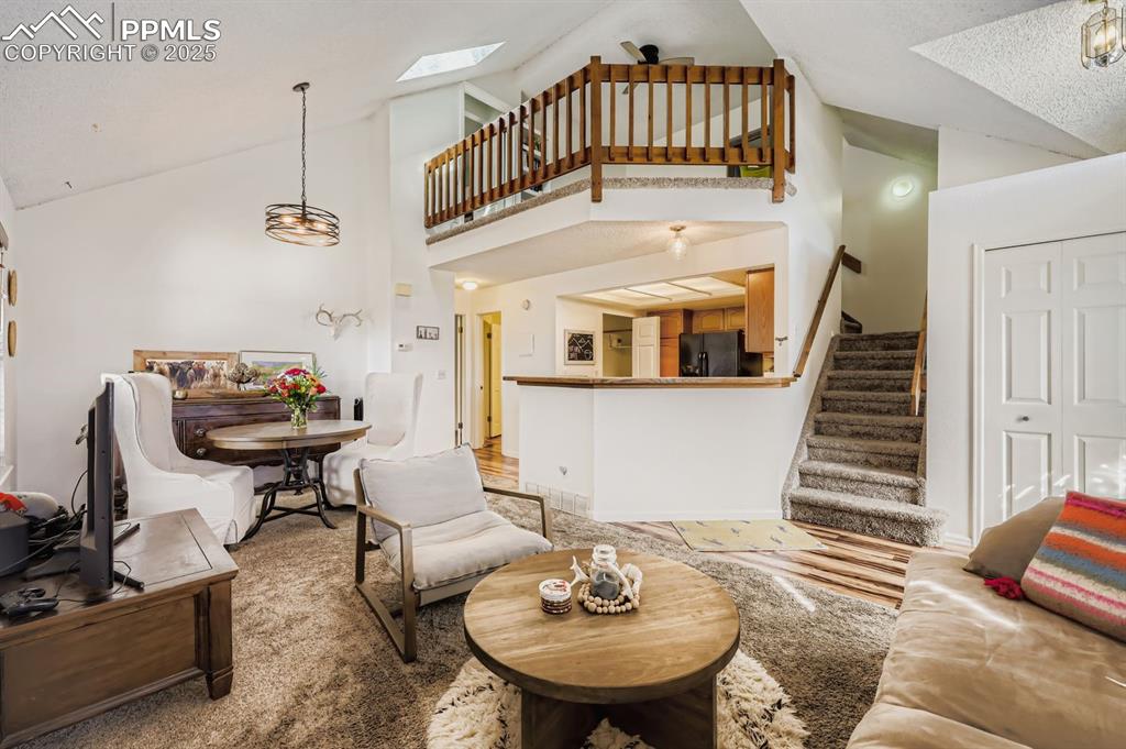Image 4 of 25: Living room featuring stairs, high vaulted ceiling, a skylight, wood finish