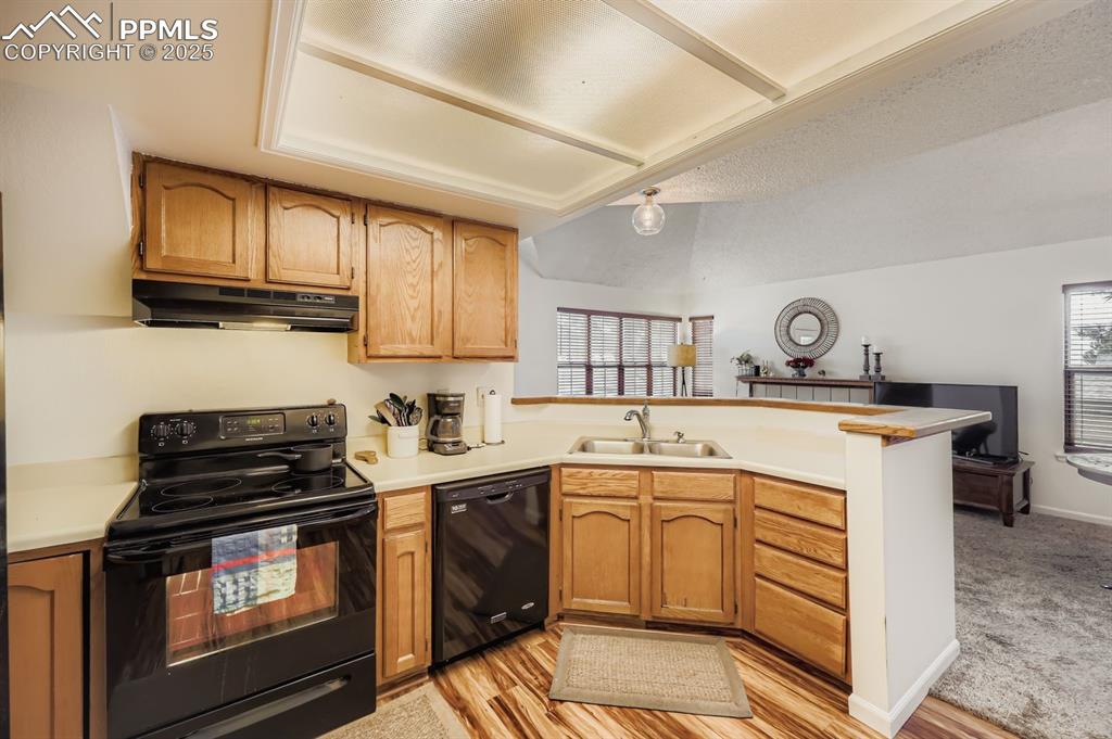 Image 7 of 25: Kitchen with black appliances, a peninsula, light countertops, under cabine