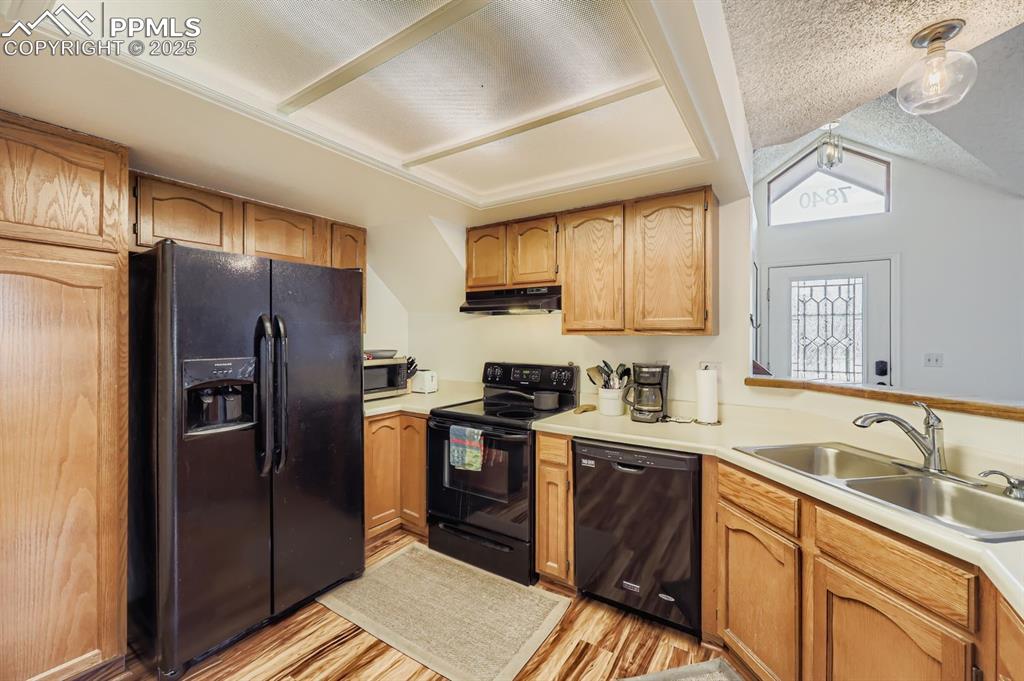 Image 8 of 25: Kitchen featuring black appliances, light countertops, light wood-style flo
