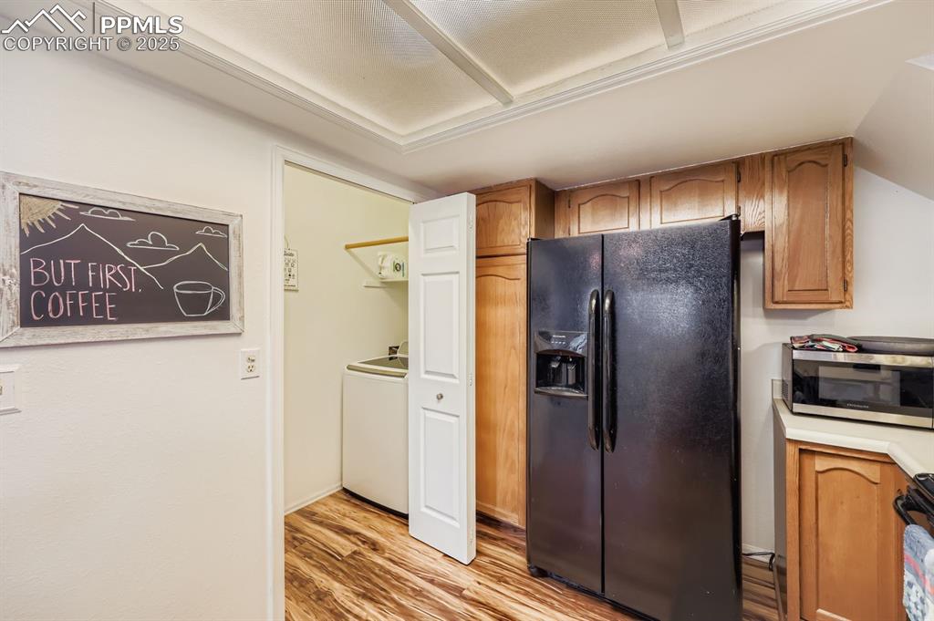 Image 9 of 25: Kitchen featuring black appliances, light wood-type flooring, light counter