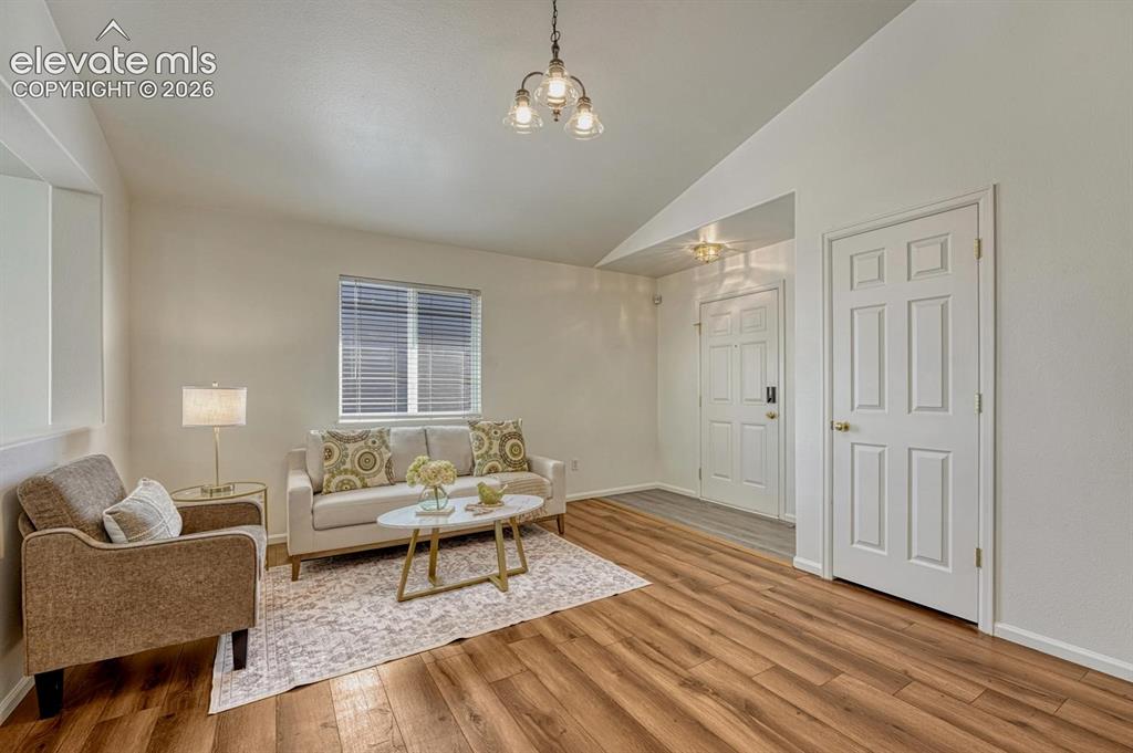 Image 12 of 35: Spacious vaulted Living Room with LVP flooring, an attractive light fixture