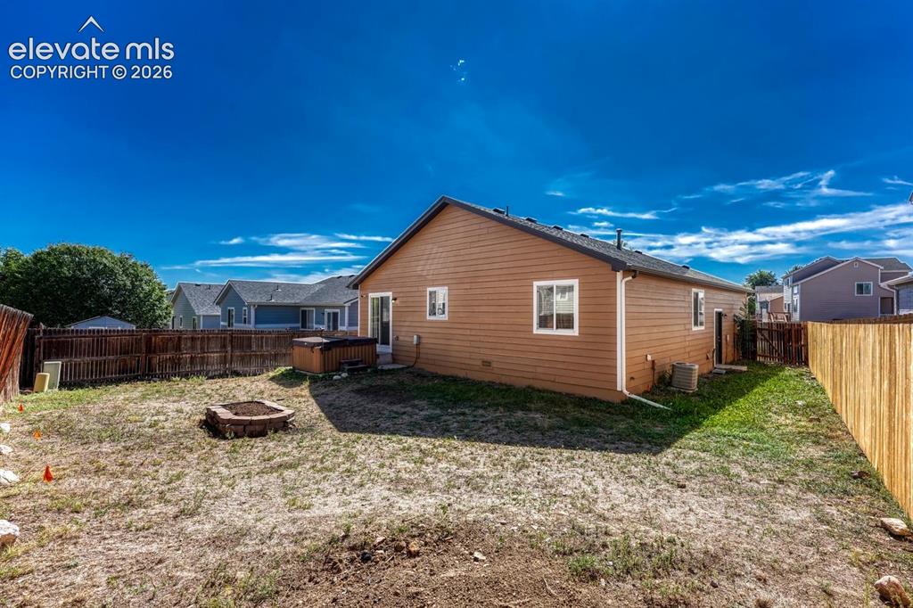 Image 30 of 35: Rear view of home and fenced backyard.