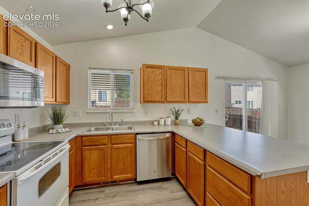 Image 4 of 35: Well-designed kitchen offers wood laminate flooring, wood cabinetry, a pant