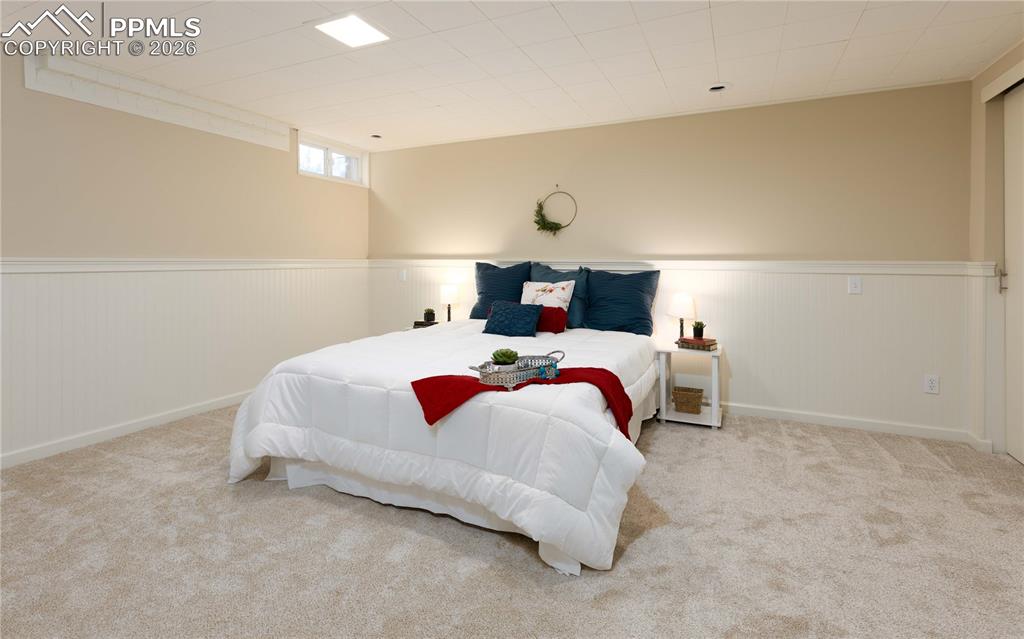 Image 15 of 29: Large basement bedroom with room darkening panels