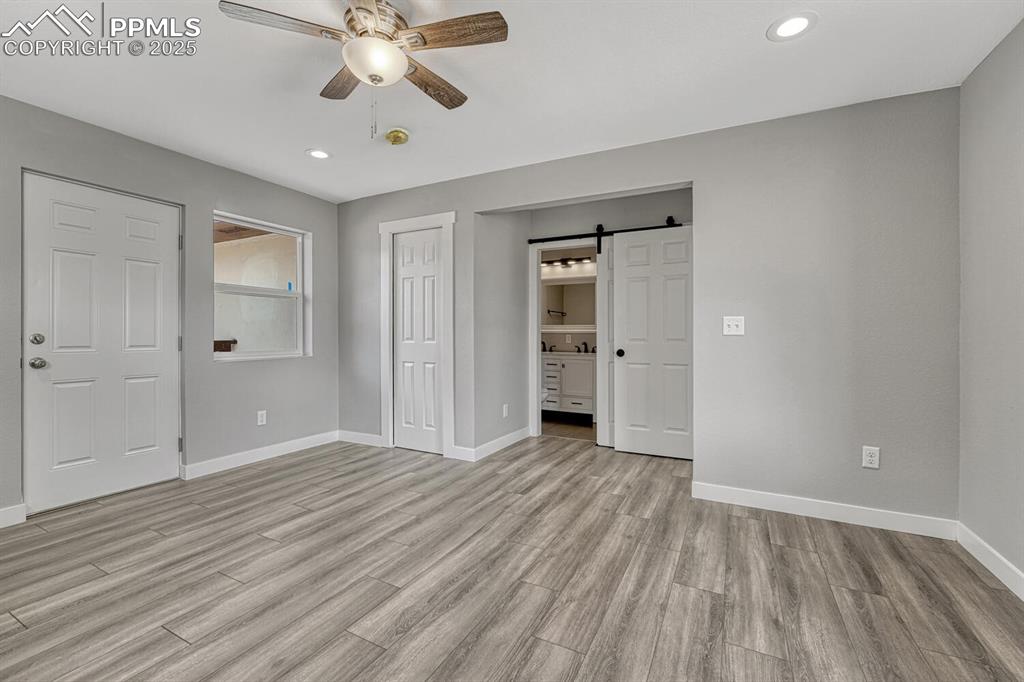 Image 17 of 50: Unfurnished bedroom featuring a barn door, recessed lighting, light wood-st