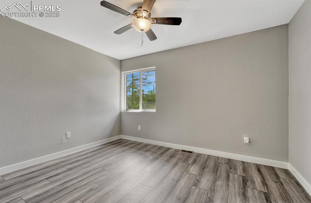 Image 22 of 50: Unfurnished room with wood finished floors, a textured wall, and ceiling fa