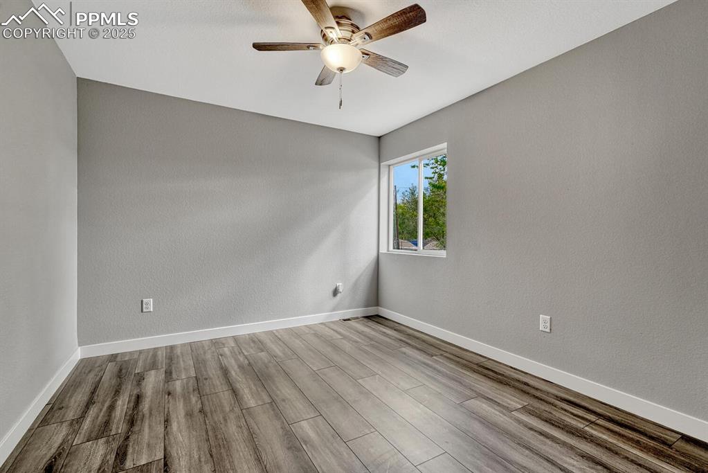 Image 26 of 50: Empty room with wood finished floors, a textured wall, and a ceiling fan