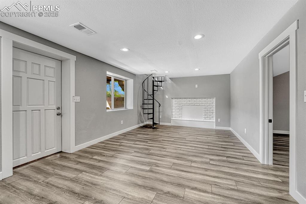Image 31 of 50: Unfurnished living room featuring stairway, a textured ceiling, light wood-