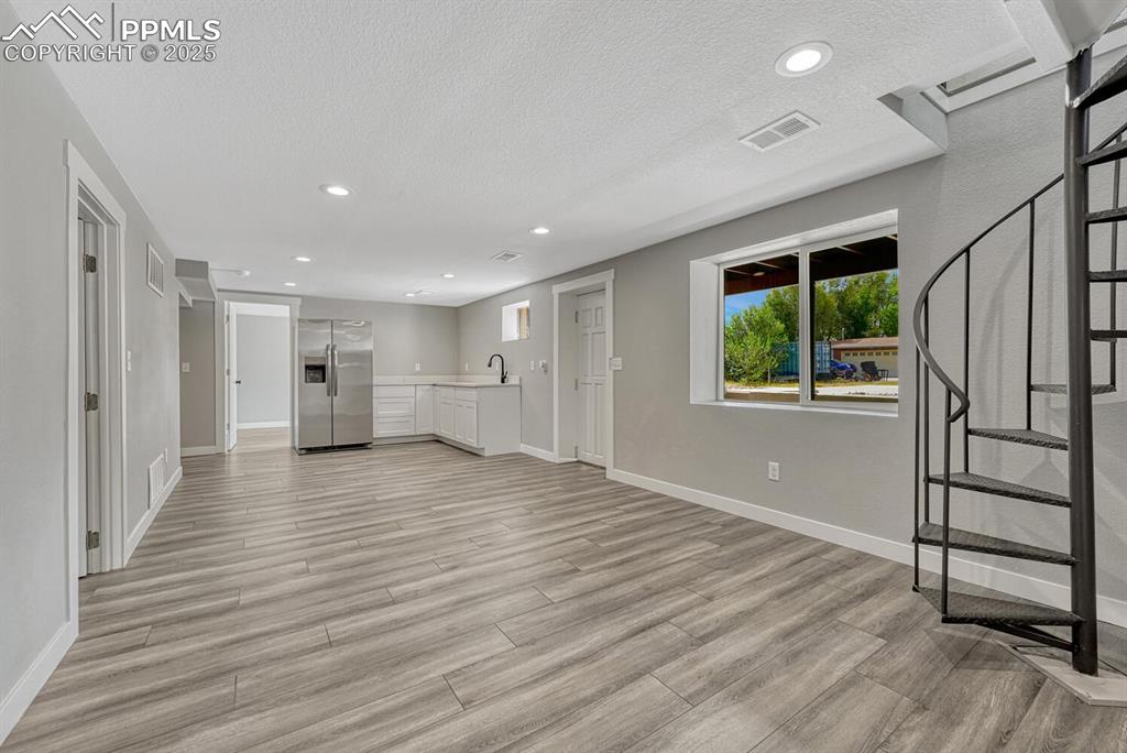 Image 32 of 50: Unfurnished living room featuring stairway, recessed lighting, light wood-s