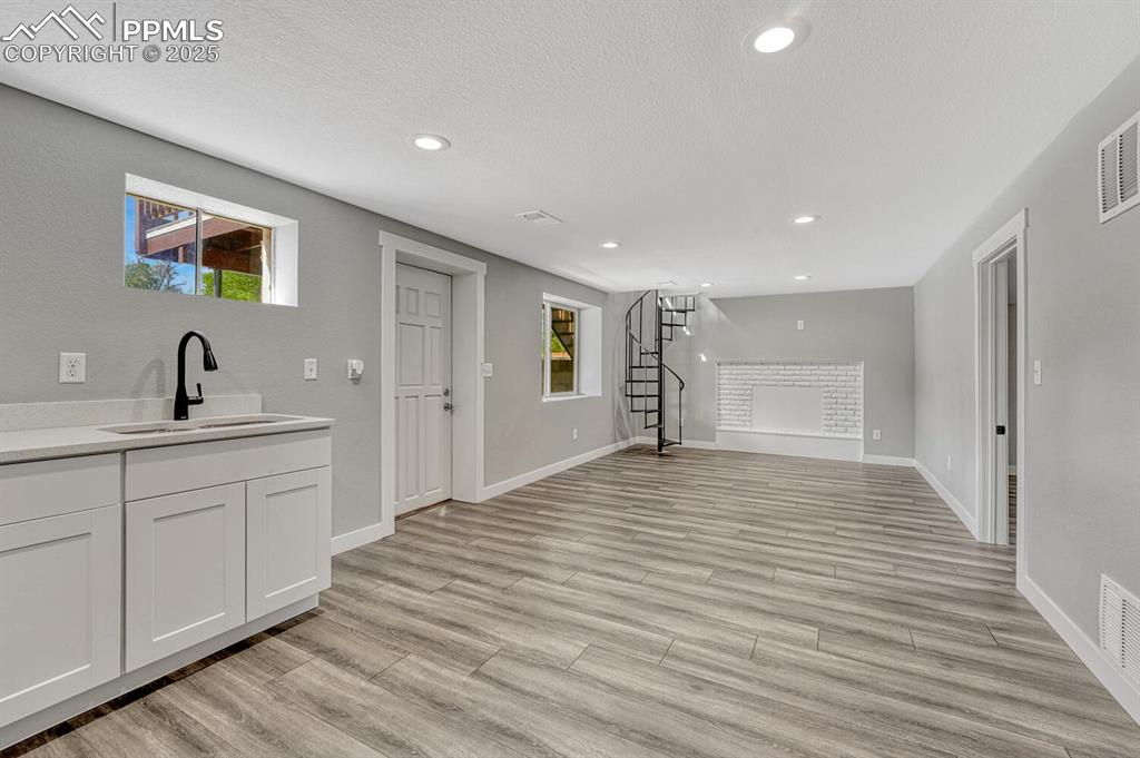 Image 35 of 50: Bar area featuring stairs, white cabinets, plenty of natural light, light w