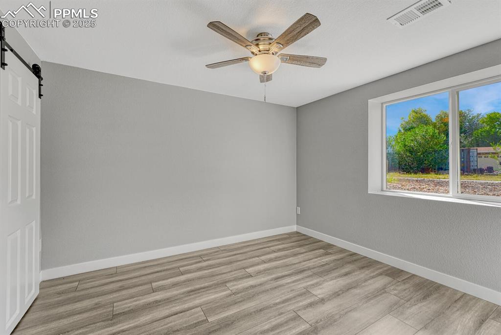 Image 36 of 50: Unfurnished room featuring a barn door, light wood-style floors, and ceilin