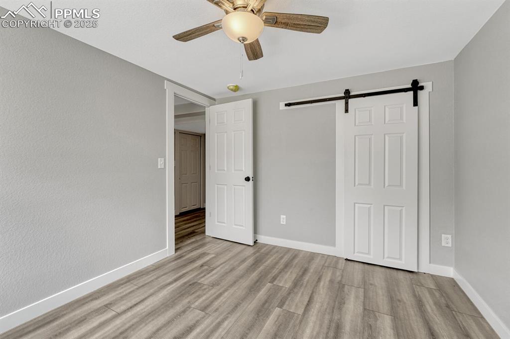 Image 37 of 50: Unfurnished bedroom with a barn door, light wood-style flooring, and ceilin