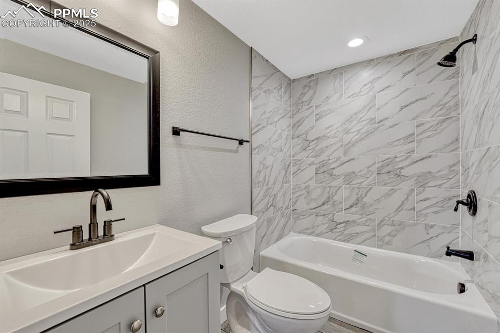 Image 39 of 50: Bathroom featuring a textured wall, shower / tub combination, and vanity