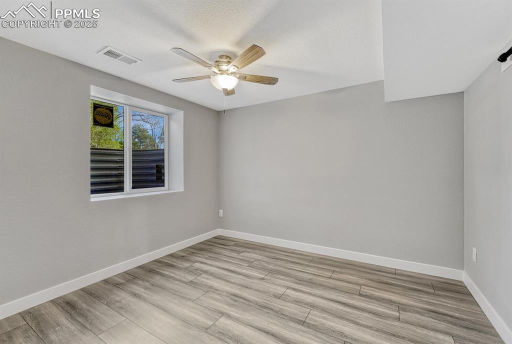 Image 40 of 50: Empty room with light wood finished floors, ceiling fan, and a textured cei