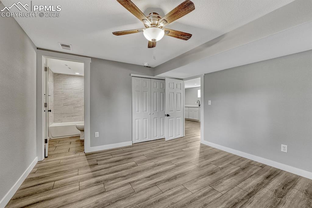 Image 44 of 50: Unfurnished bedroom featuring light wood-type flooring, ceiling fan, a clos