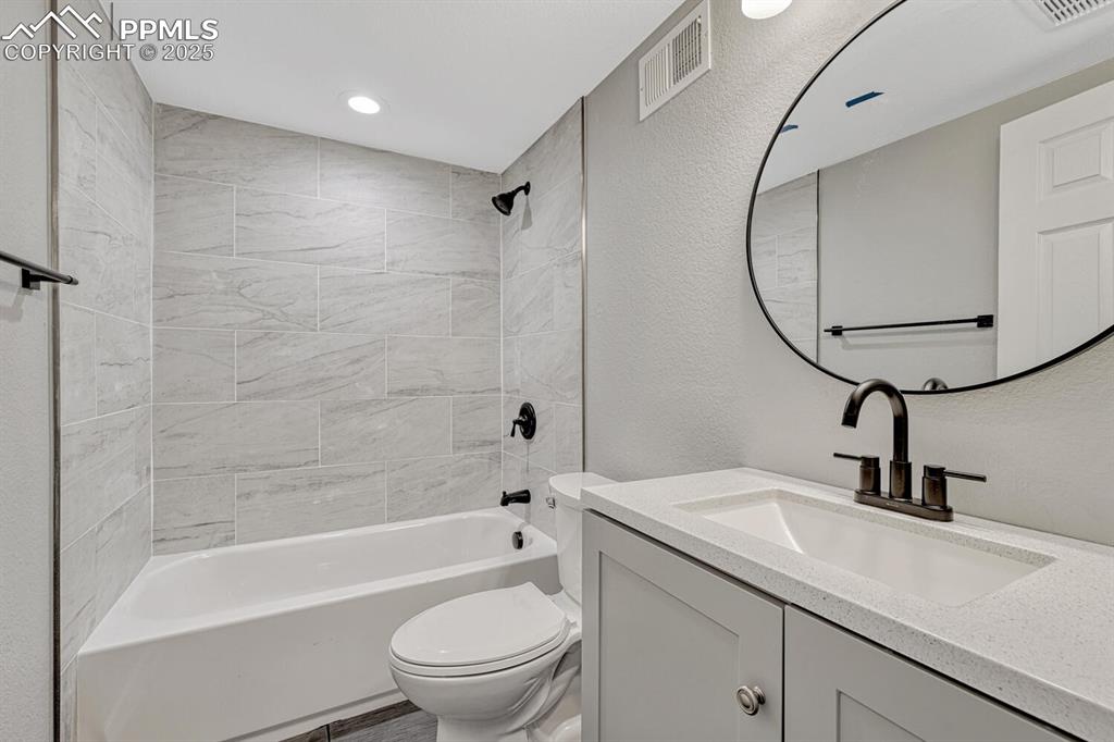 Image 46 of 50: Bathroom with a textured wall, tub / shower combination, and vanity
