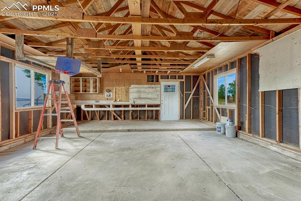Image 48 of 50: Misc room with unfinished concrete floors and a garage