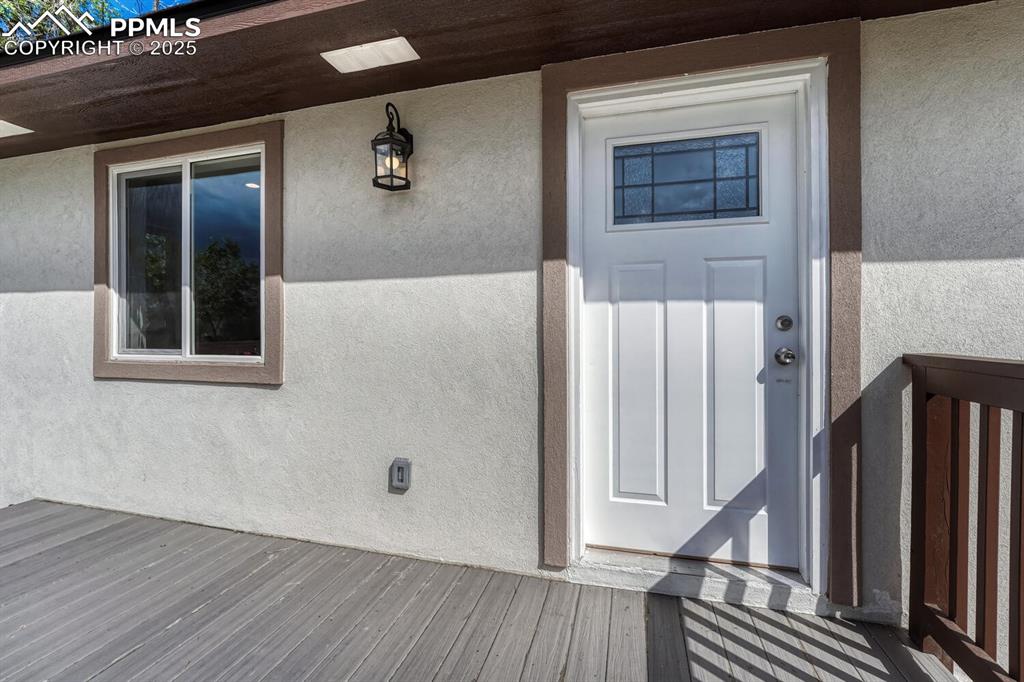 Image 5 of 50: View of exterior entry with stucco siding and a deck