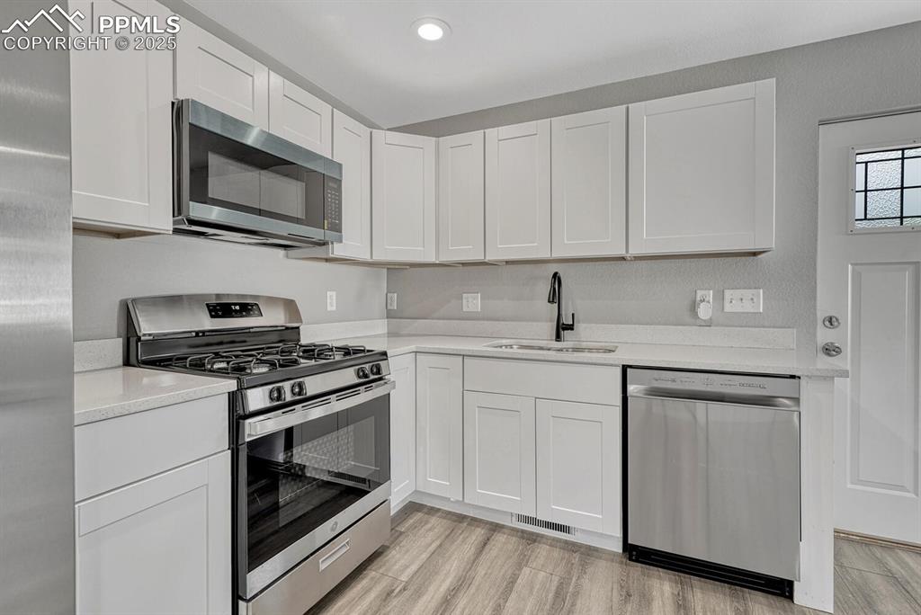 Image 8 of 50: Kitchen featuring appliances with stainless steel finishes, white cabinetry