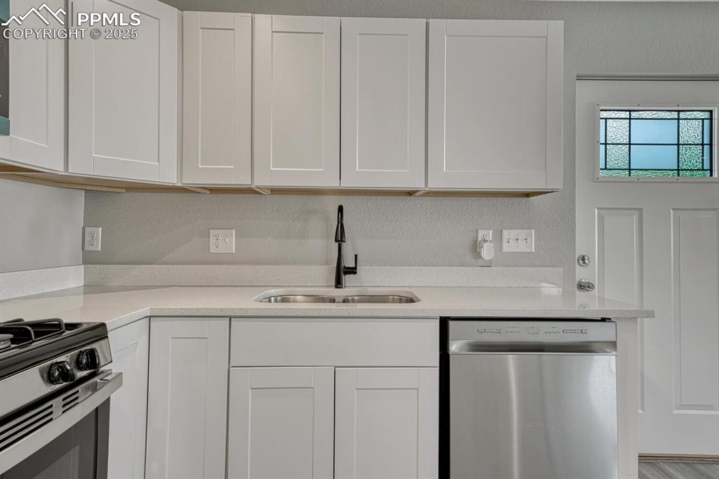 Image 9 of 50: Kitchen featuring white cabinets, appliances with stainless steel finishes,