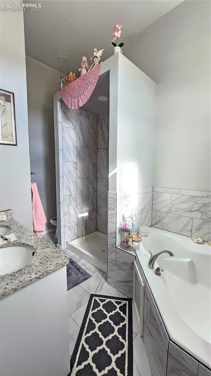 Image 15 of 48: Bathroom featuring marble finish floor, tiled shower, vanity, and a bath