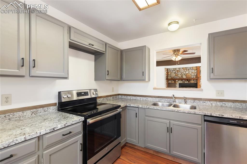Image 10 of 27: The kitchen features gray cabinets, stainless steel appliances, and light c
