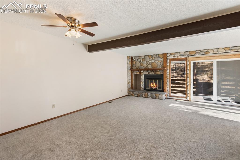 Image 3 of 27: The living room with carpet flooring, a fireplace with stone accents, a bea